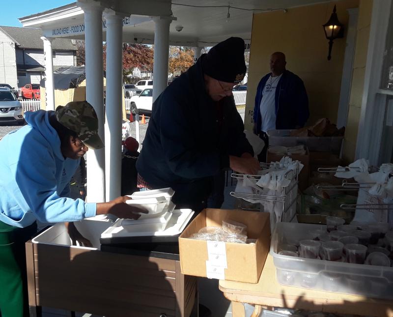 Volunteers prepare Thanksgiving dinner takeout boxes on the porch.
